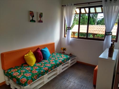 a couch with colorful pillows in a room with a window at Casa Linda Ilhabela in Ilhabela