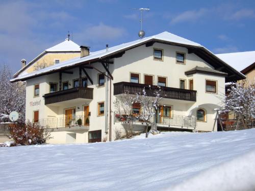 un grand bâtiment avec de la neige au sol dans l'établissement Mairhof, à Laion