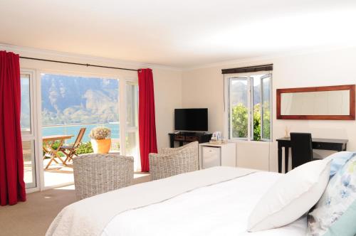 a bedroom with a bed and chairs and a balcony at Hout Bay Breeze in Hout Bay