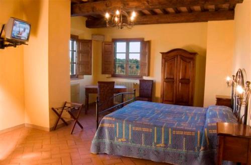 a bedroom with a bed and a table and a television at Agriturismo Colleoli in Palaia