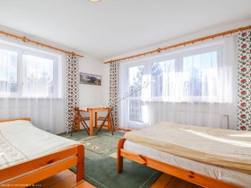 a bedroom with two beds and two windows at Gościniec nad potokiem in Jurgów