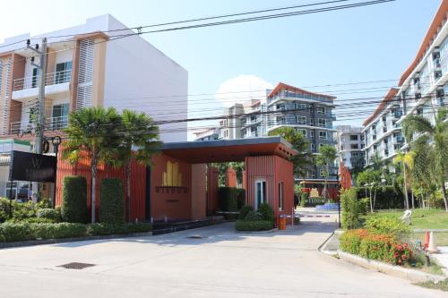 a building on a street with palm trees and buildings at Wisdom Hotel & Residence in Rayong