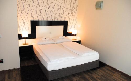 a bedroom with a large bed with two lamps on it at Vila DeLux in Negotin