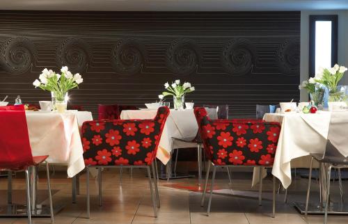 a dining room with white tables and red chairs at Anessis in Thessaloniki