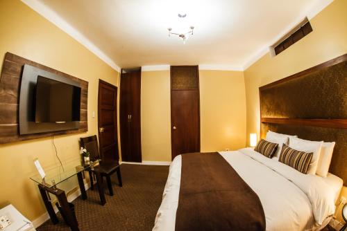 a hotel room with a bed and a flat screen tv at Los Leones Hotel Boutique in Arequipa