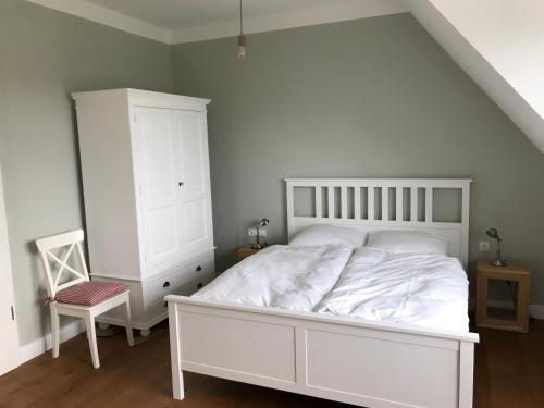 a bedroom with a white bed and a chair at Ferien Hohes Elbufer in Schnakenbek