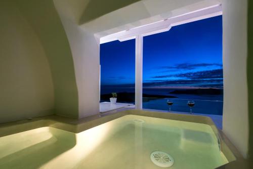 a bath tub in a room with a large window at Iriana Suites in Fira