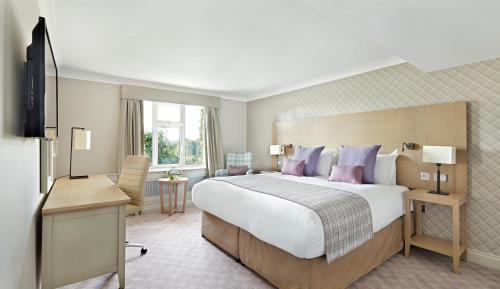 Habitación de hotel con cama grande y escritorio. en The Belfry Hotel & Resort en Sutton Coldfield