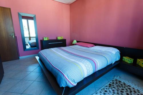 1 dormitorio con cama y pared de color rosa en Casa Guia, en Marina di Cecina