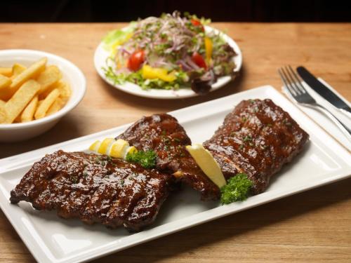 a white plate with ribs and a salad and fries at Hotel Restaurant St. Lambert in Helmond