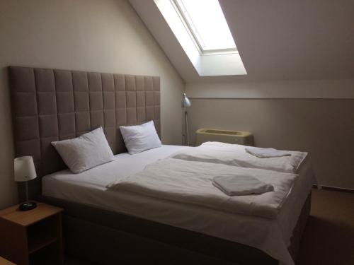 a bedroom with a large white bed with a skylight at Penzion a restaurace U Hroznu in Velké Bílovice