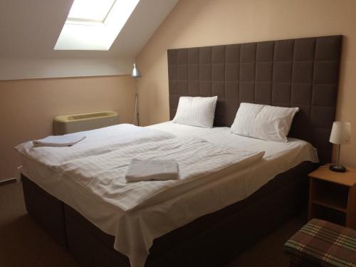 1 dormitorio con 1 cama grande con sábanas blancas en Penzion a restaurace U Hroznu en Velké Bílovice