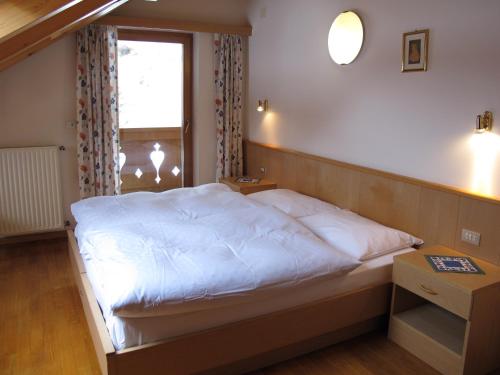a bedroom with a white bed with a window at Ciasa Ardoney in Campitello di Fassa
