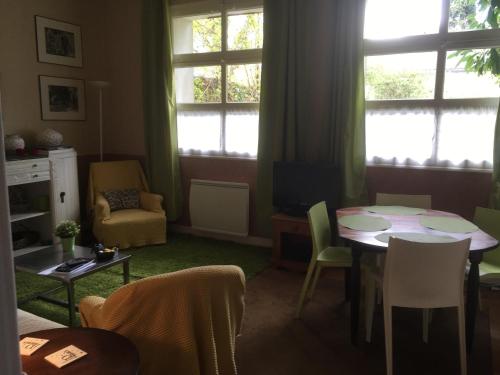 uma sala de estar com uma mesa, cadeiras e janelas em La Chevalerie em Bléré