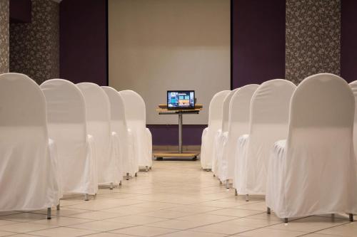 a row of white chairs in a room with a computer at Hotel Real Azteca Boulevard in León