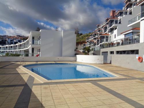 a swimming pool in front of a building at Paradisus Stylish Family Living in a 3-Bedroom Condo with Pool in Caniço