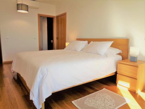 a bedroom with a large white bed and a night stand at Paradisus Stylish Family Living in a 3-Bedroom Condo with Pool in Caniço