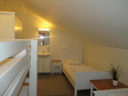 um pequeno quarto com uma cama e um lavatório em Munkebergs Stugor & Vandrarhem em Filipstad