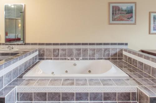 een bad in een badkamer met een tegelvloer bij The Schenectady Inn & Suites in Schenectady