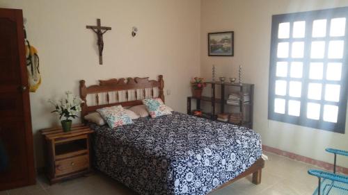 1 dormitorio con 1 cama y 1 cruz en la pared en Casa Trujeque, en Sisal