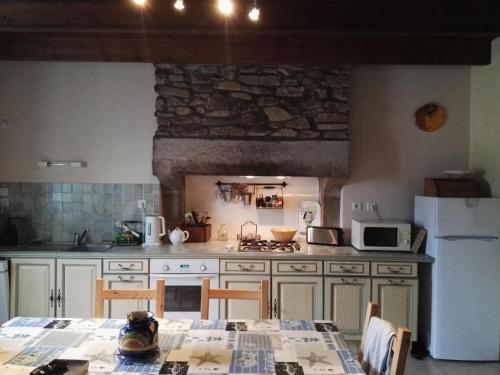 a kitchen with a table and a white refrigerator at Côte de granit rose in Pleumeur-Bodou