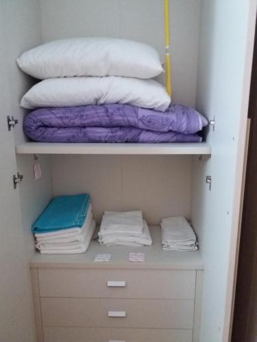 um armário cheio de almofadas brancas e roxas em Domus Sottoripa em Gênova