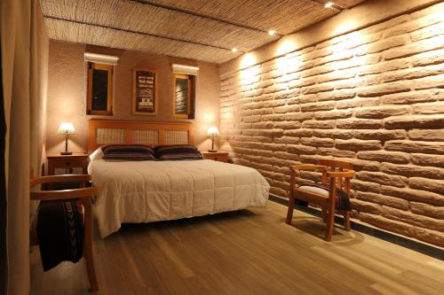 a bedroom with a bed and a stone wall at La Casa de Pascual Andino in San Pedro de Atacama