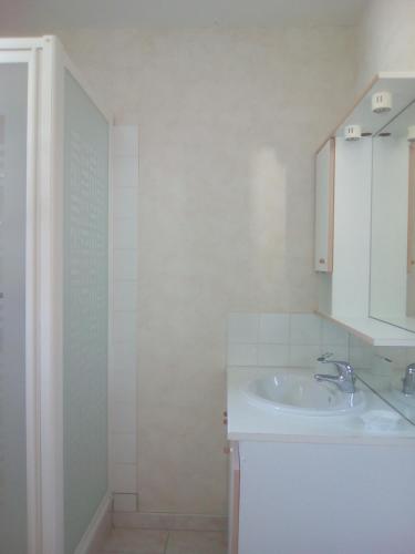 une salle de bain blanche avec un lavabo et une douche dans l'établissement La belle étape, à Sérignan