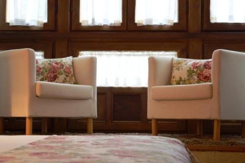 two chairs and a bed in a room with windows at Casona del Nansa in Herrerias