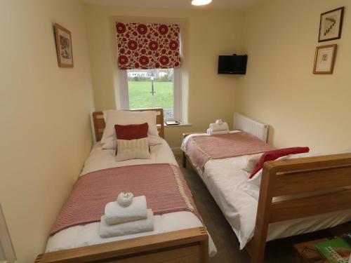 two twin beds in a room with a window at Inglenook Guest House in Ingleton 