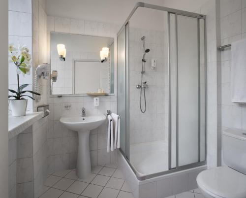 a white bathroom with a shower and a sink at Hotel MDM City Centre in Warsaw