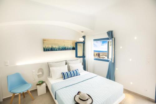 a white bedroom with a bed and a blue chair at Amera Suites in Fira