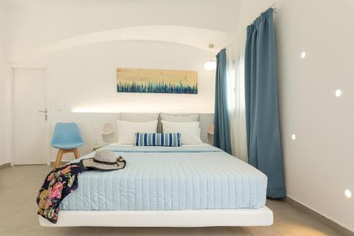 a bedroom with a bed and a blue chair at Amera Suites in Fira