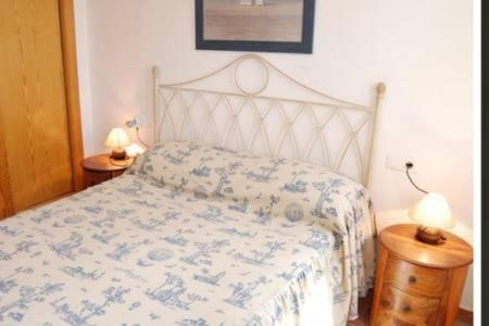 a bed in a bedroom with two lamps on tables at Apartamento en Nerja in Nerja