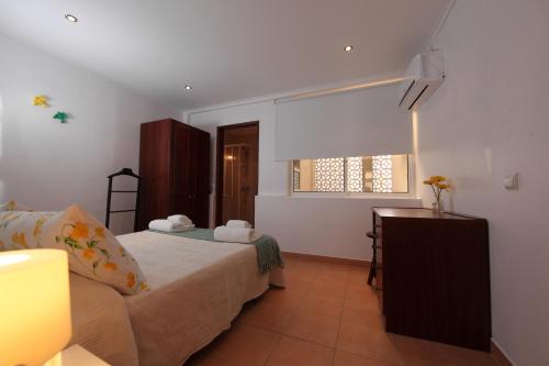 a bedroom with a bed and a desk and a window at Casa das Andorinhas in Faro