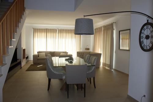 a dining room and living room with a table and chairs at Praia Del Rei Private Pool Beach Golf in Amoreira