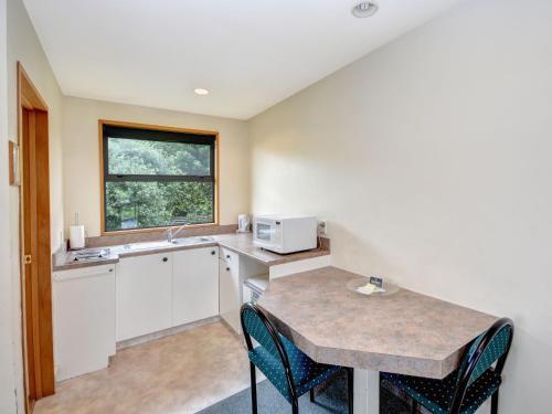 a kitchen with a counter and a table with chairs at Bonnie Knights Motel Mosgiel in Mosgiel