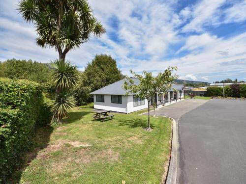 a white house with a picnic table next to a street at Bonnie Knights Motel Mosgiel in Mosgiel