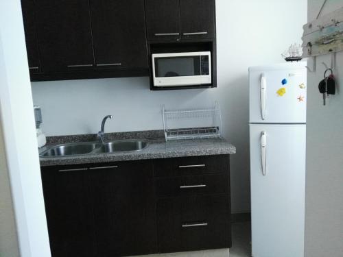a kitchen with a sink and a white refrigerator at Departamento amoblado Manta in Manta