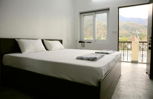 a bedroom with a large bed with a large window at Sanidhya Inn in Rishīkesh