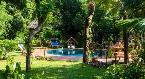 a pool in a yard with a person sitting in a chair at Sang Tong Huts in Mae Hong Son