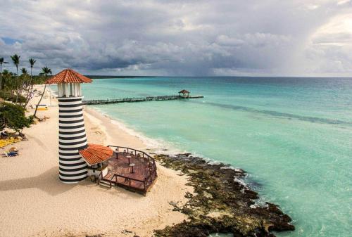 a beach with a lighthouse and chairs and the ocean at Habitacion en Sol Dominicus solo adultos in Bayahibe