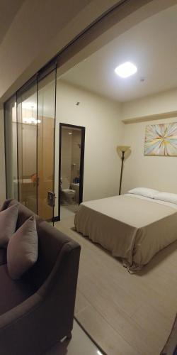 um quarto com uma cama grande e um sofá em Mactan Newtown Seaview at One Pacific Residence em Mactan