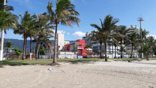a beach with palm trees and a red building at Pousada Cantinho Oriental in Bertioga