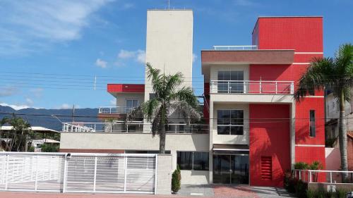 a red and white building with palm trees in front of it at Pousada Cantinho Oriental in Bertioga
