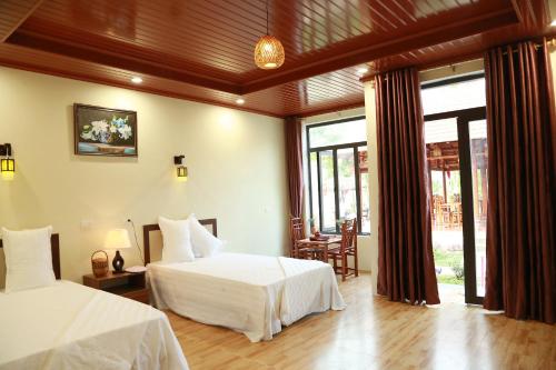 a bedroom with two beds and a large window at Son River House in Phong Nha