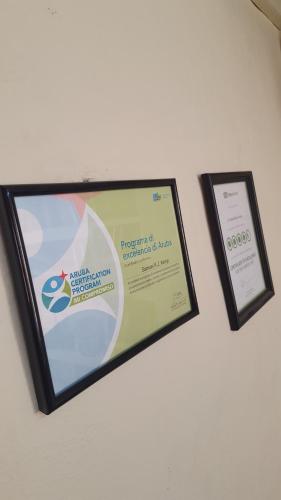 two framed certificates and a sign on a wall at A1 Apartments Aruba in Oranjestad