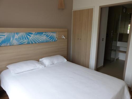 1 dormitorio con 1 cama blanca y 2 almohadas en Le Pacifik Kone, en Koné