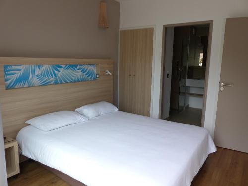 1 dormitorio con 1 cama blanca y sábanas blancas grandes en Le Pacifik Kone, en Koné