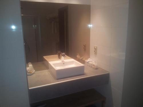 y baño con lavabo blanco y espejo. en Hotel Belvedere, en Heuvelland